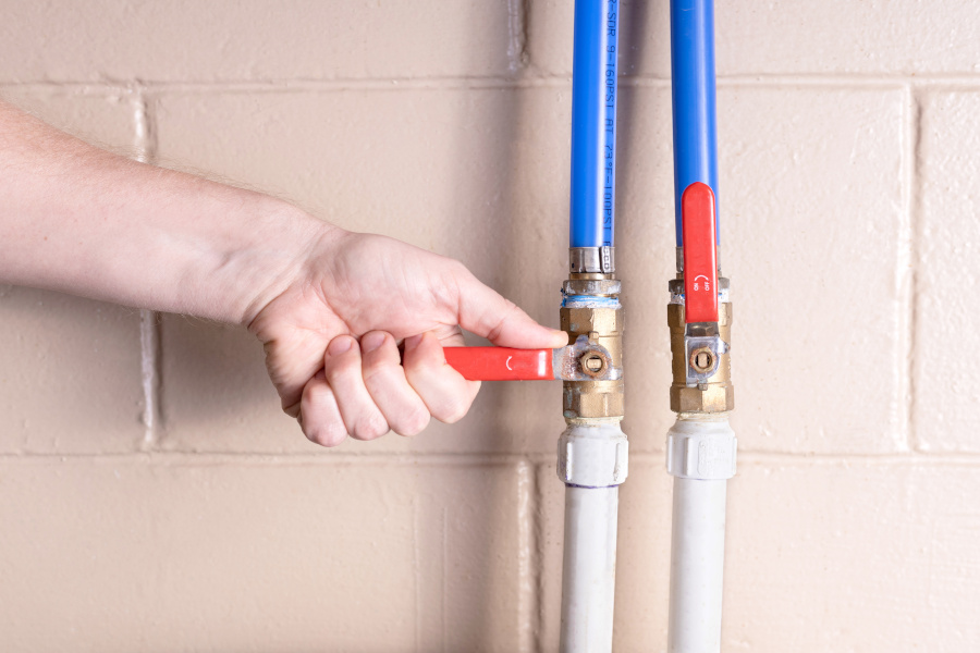 A person turning a main water shut off valve off. Son-Rise Plumbing helps with water shut off valves that leak or don't properly close.
